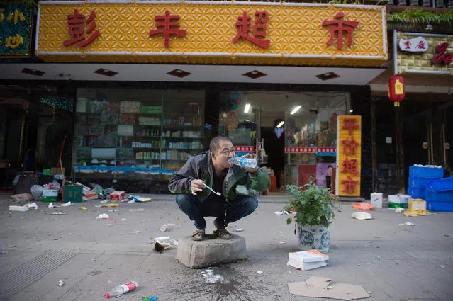 A resident brushes his teeth outside his shop after an earthquake in Zhangzha in southwest China' s Sichuan province on August 10, 2017. The 6.5- magnitude earthquake struck Sichuan province late on August 8, tearing cracks in mountain highways, triggering landslides, damaging buildings and sending panicked residents and tourists fleeing into the open. (Photo by Nicolas Asfouri/AFP Photo)