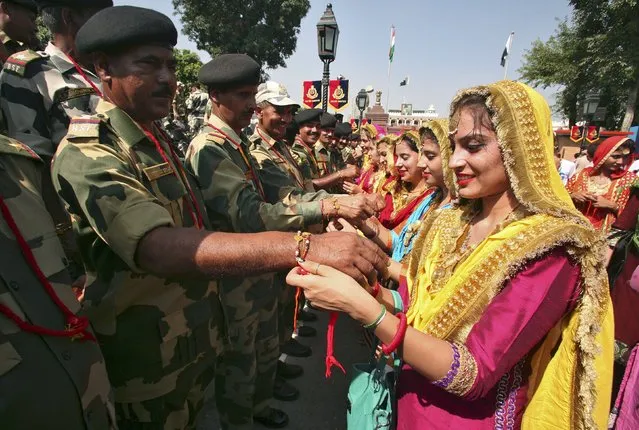 Indian women tie “Rakhis” or traditional Indian sacred threads onto the wrists of Indian Border Security Force (BSF) soldiers during the Raksha Bandhan celebrations at the India-Pakistan joint check post at the Wagah border on the outskirts of Amritsar, India, August 29, 2015. (Photo by Munish Sharma/Reuters)