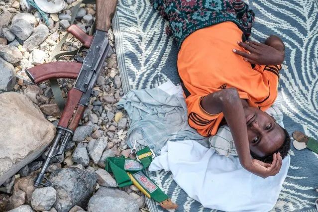 An internally displaced man, member of the Afar militia, lies on the floor next to a weapon in the makeshift camp where they he is sheltered in the village of Erebti, Ethiopia, on June 09, 2022. The Afar region, the only passageway for humanitarian convoys bound for Tigray, is itself facing a serious food crisis, due to the combined effects of the conflict in northern Ethiopia and the drought in the Horn of Africa which have notably caused numerous population displacements. More than a million people need food aid in the region according to the World Food Programme. (Photo by Eduardo Soteras/AFP Photo)