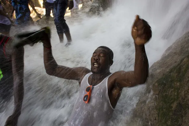 In this July 16, 2016 photo, a Voodoo pilgrim bathes in a waterfall believed to have purifying powers during the annual celebration in Saut d' Eau, Haiti. Annually, the falls are the site of a large, important religious pilgrimage, during the festival of Our Lady of Carmel, as well as various Voodoo rituals. (Photo by Dieu Nalio Chery/AP Photo)