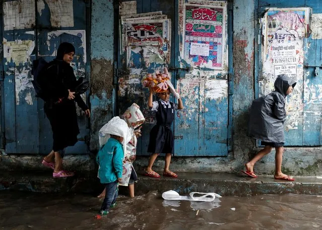 A woman accompanies schoolchildren through a flooded street during monsoon rains in Mumbai, India, August 1, 2016. (Photo by Danish Siddiqui/Reuters)