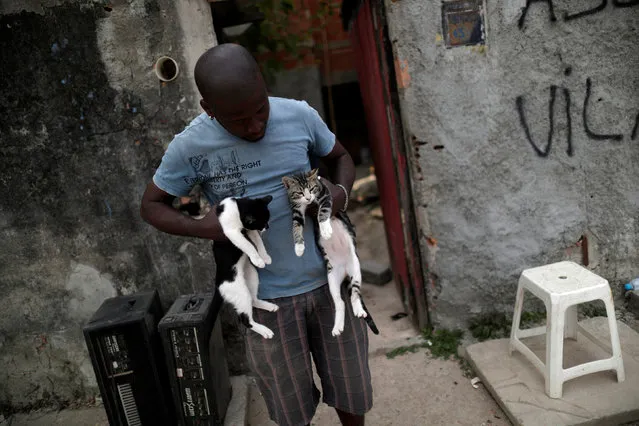 Wanderson Augusto, who has lived in Vila Autodromo slum for 20 years, holds his cats before his house gets demolished, after moving to one of the twenty houses built for the residents who refused to leave the community, in Rio de Janeiro, Brazil, August 2, 2016. (Photo by Ricardo Moraes/Reuters)
