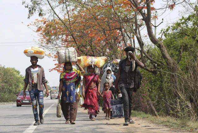 Migrant workers from Chhattisgarh state carry their belongings and make the journey to their village hundreds of miles away on foot during a nationwide lockdown to curb the spread of new coronavirus in Hyderabad, India, Friday, May 8, 2020. Locking down the country's 1.3 billion people has slowed down the spread of the virus, but has come at the enormous cost of upending lives and millions of lost jobs. (Photo by Mahesh Kumar A./AP Photo)