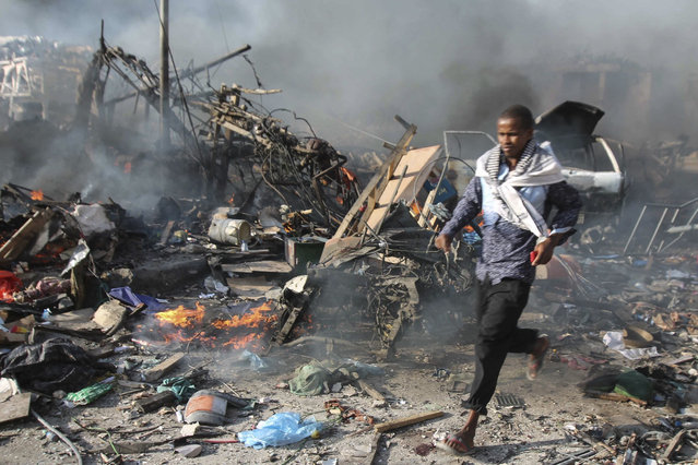 A man runs through the scene of a massive explosion in front of Safari Hotel in the capital Mogadishu, Somalia, 14 October 2017. Reports state at least 20 peole have been killed when a truck bomb went off on a busy street in central Mogadishu. There was no immediate claim of responsibility but the country's Islamist militant group al-Shabab often carries out similar attacks in the capital. (Photo by Said Yusuf Warsame/EPA)