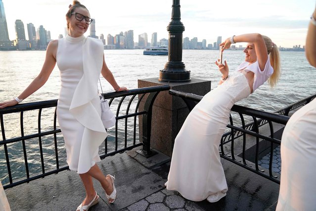 Julia Gracheva and Anna Speak takes photos as they attend the 10th edition of “Diner en Blanc” at Brookfield Place in Lower Manhattan September 19, 2022. The legendary all-white secret pop-up, the location of which is revealed hours before the event, draws over 5,500 guests who dress in head-to-toe white attire for an under the stars dining experience. (Photo by Timothy A. Clary/AFP Photo)
