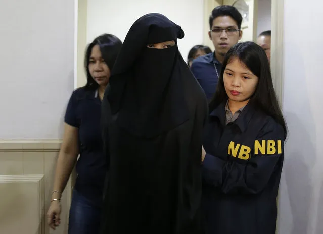 Wearing a burqa, Karen Aizha Hamidon, the widow of the leader of a militant band allegedly sympathetic to the Islamic State group, is escorted by security after a news conference at the National Bureau of Investigation in Manila, Philippines, on Wednesday, October 18, 2017. Authorities arrested Hamidon and said she recruited foreign fighters to the country and spread extremist propaganda. (Photo by Aaron Favila/AP Photo)