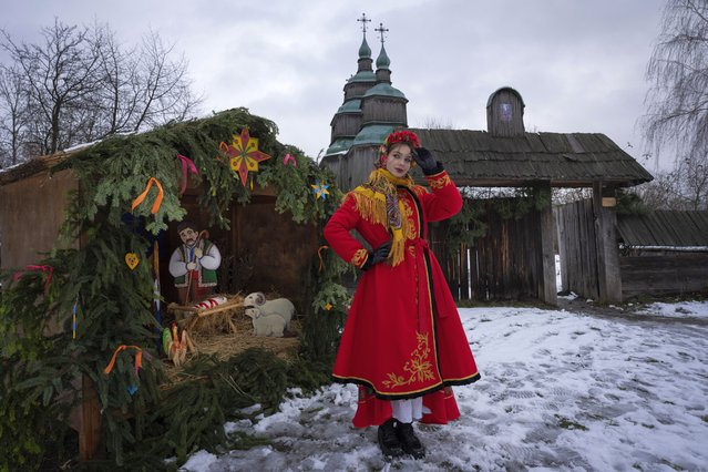 A woman dressed in national costume stands near the nativity scene to celebrate Christmas in the village of Pirogovo, outside the capital Kyiv, Ukraine, Monday, December 25, 2023. (Photo by Efrem Lukatsky/AP Photo)