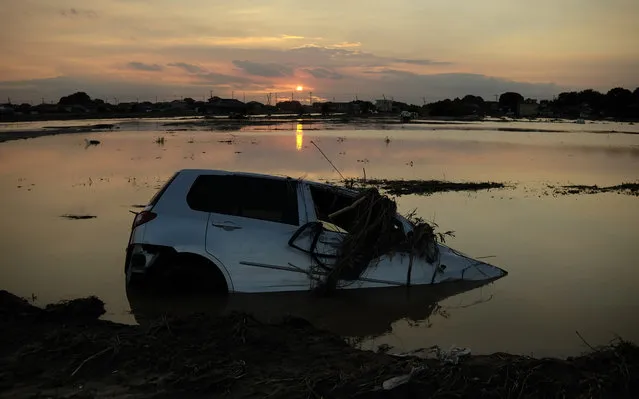 The sun sets behind the wreckage of a vehicle submerged in floodwaters in Joso city, Ibaraki prefecture on September 11, 2015. (Photo by Kazuhiro Nogi/AFP Photo)