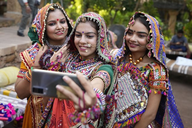 Women wearing traditional attire take a selfie as they practice the Garba, the traditional dance of Gujarat state, ahead of Navratri in Ahmedabad, India, Tuesday, September 20, 2022. The Hindu festival of Navratri, or nine nights, will begin Sept. 26. (Photo by Ajit Solanki/AP Photo)