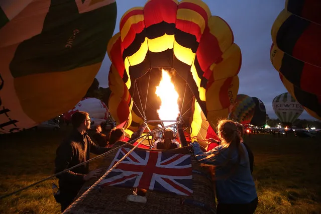 Balloons are inflated during the “nightglow” at the Bristol International Balloon Fiesta in Bristol, Britain August 11, 2016. (Photo by Neil Hall/Reuters)
