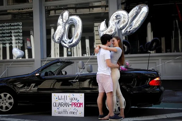 Diego Torres from Riverdale High School, surprises his girlfriend Gabi Dubrul from Professional Children's School outside her family's apartment with balloons, flowers and a sign in the Soho neighborhood of Manhattan, New York, May 26, 2020. (Photo by Mike Segar/Reuters)