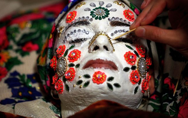 Bulgarian Muslim bride Aysel Gerova, 24, has makeup applied to her face during her wedding ceremony in the village of Ribnovo, in the Rhodope Mountains, Bulgaria, December 17, 2023. The village of Ribnovo has kept its traditional winter marriage ceremony alive after decades of Communist rule. The wedding ritual was resurrected among the Pomaks. The highlight of the ceremony is the painting of the bride's face, where in a private rite open only to female in-laws, her face is covered in thick, chalky white paint and decorated with colourful sequins. (Photo by Stoyan Nenov/Reuters)