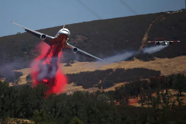 A DC-10 fire fighting aircraft (L) makes a fire retardant drop while following its lead plane while battling the Clayton Fire north of Lower Lake in California, U.S. August 15, 2016. (Photo by Stephen Lam/Reuters)