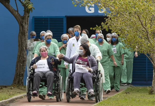 Iracema Djeane, left, and her 41-year-old daughter Carolina Djeane celebrate as they hold signs that read in Portuguese “I defeated the COVID-19”, after being released from a field hospital built inside a gym to treat COVID-19 patients in Santo Andre, on the outskirts of Sao Paulo, Brazil, Tuesday, June 9, 2020. (Photo by Andre Penner/AP Photo)