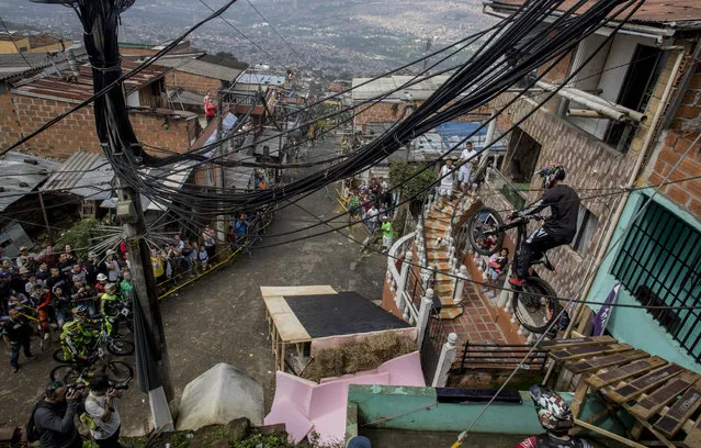 Residents watch as a downhill rider competes during the Urban Bike Inder Medellin race final at the Comuna 1 shantytown in Medellin, Antioquia department, Colombia on November 19, 2017. (Photo by Joaquin Sarmiento/AFP Photo)