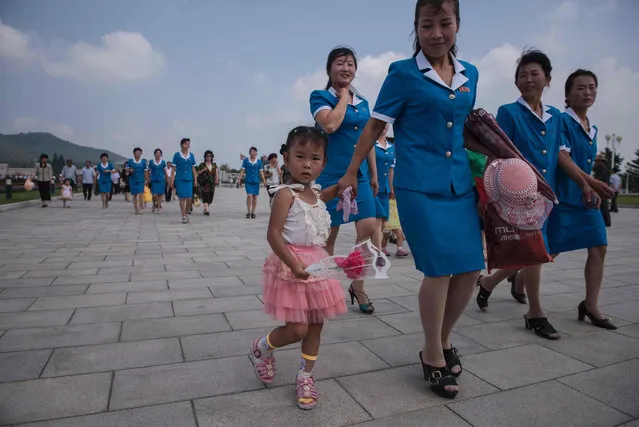 A group of North Korean workers and a child walk to pay their respects to late North Korean leader Kim Il-Sung on the anniversary of his death, outside the Kumsusan Palace of the Sun mausoleum in Pyongyang on July 8, 2016. (Photo by Ed Jones/AFP Photo)