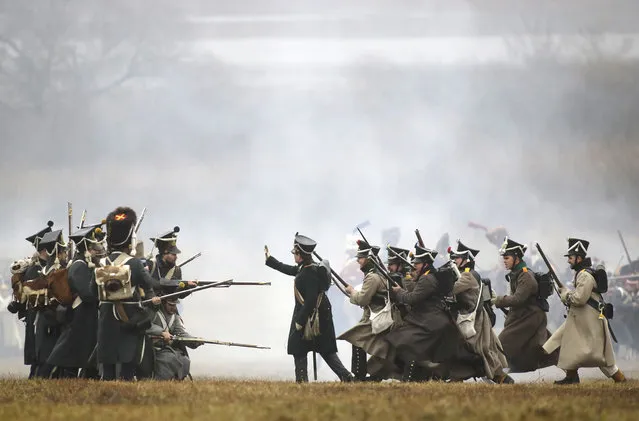 Men dressed as 1812-era Russian and French soldiers re-enact a staged battle near the Belarus village of Bryli, about 115 kilometers (70 miles) east of the capital, Minsk, Sunday, November 26, 2017, to mark the 205th anniversary of the Berezina battle during Napoleon's army retreat from Russia. The retreat across the Berezina of the remnants of Napoleon's Grand Army, which invaded Russia June 24, 1812, took place from Nov. 26 to Nov. 29, 1812. (Photo by Sergei Grits/AP Photo)