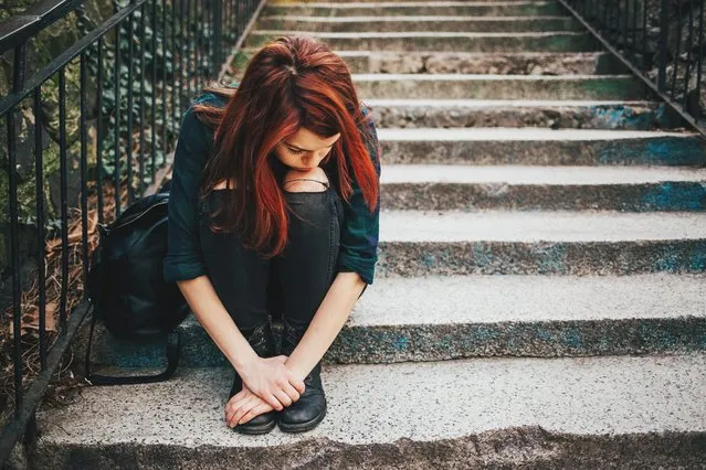 Depressed young woman sitting on stairs outdoors, with copy space. (Photo by Pixelfit/Getty Images)