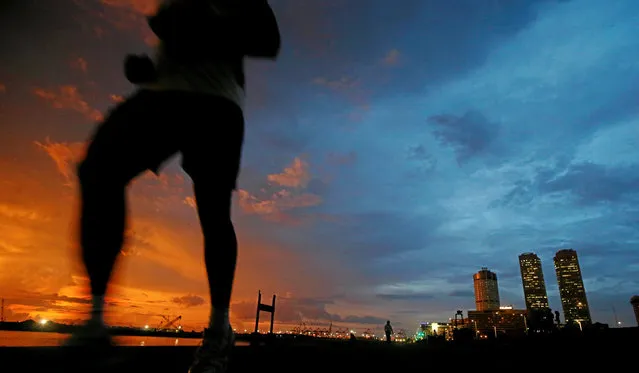 Financial district of Colombo is seen as a man runs along a path in front of the China invested Colombo Port City construction site in Colombo, Sri Lanka November 22, 2017. (Photo by Dinuka Liyanawatte/Reuters)