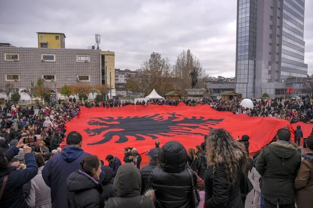 People wave a giant Albanian national flag during a celebration marking the 110th anniversary of the Albanian Independence, in Pristina on November 28, 2022. (Photo by Armend Nimani/AFP Photo)