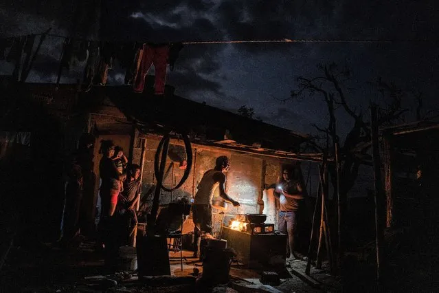 The Ramos family cooks dinner over a fire outside their storm-damaged home that continues without electricity one week after Hurricane Ian in La Coloma, Pinar del Rio province, Cuba, Wednesday, October 5, 2022  (Photo by Ramon Espinosa/AP Photo)