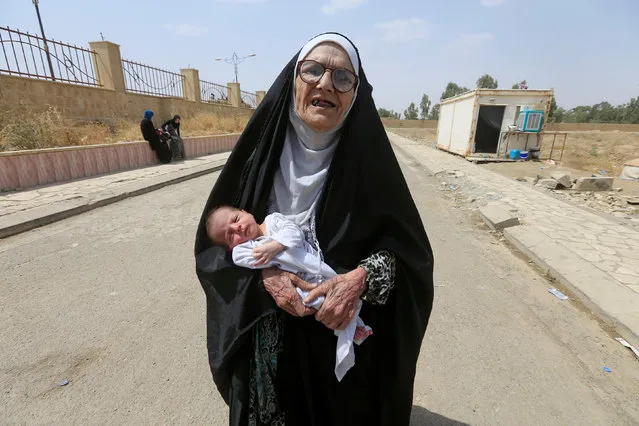 An elderly displaced Iraqi woman who fled from Islamic State militants carries a baby in Mosul, Iraq July 3, 2017. (Photo by Alaa Al-Marjani/Reuters)