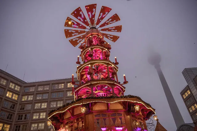 Wooden figures stand on several floors in a Christmas pyramid at the annual Christmas market at Alexanderplatz, close to the Berliner Fensehturm (TV-Tower), one of many in the city, on November 30, 2022 in Berlin, Germany. Christmas markets have been opening across Germany for the first time without any restrictions since the coronavirus pandemic began. (Photo by Carsten Koall/Getty Images)