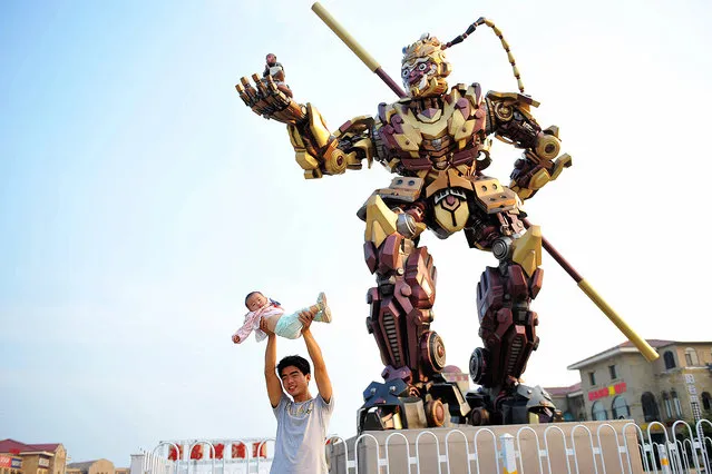A visitor shows off his baby in front of a statue of the Monkey King in Qingdao, China on September 12, 2016. (Photo by Yu Fangping/ZUMA Press/Splash News)
