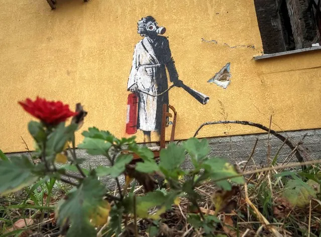 A new graffiti in Banksy's signature style, although not posted by the mercurial artist on social media, is seen on the wall of a destroyed building in the Ukrainian town of Hostomel, which had been occupied by Russia until April and heavily damaged by fighting in the early days of Russian invasion on November 13, 2022. (Photo by Gleb Garanich/Reuters)