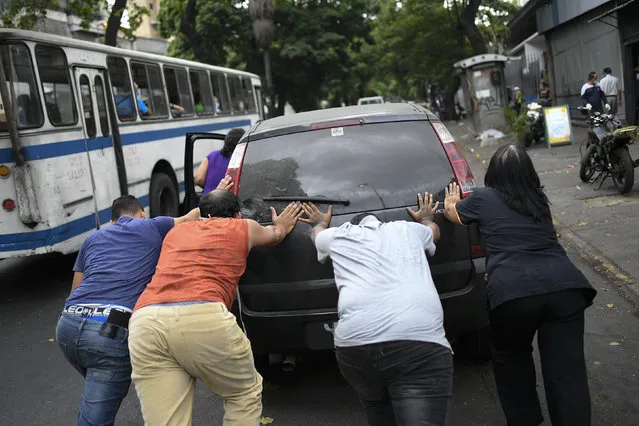 In this May 25, 2020 file photo, people push a car that ran out of gas to a state-run oil company PDVSA filling station during a fuel crunch in Caracas, Venezuela. With motorists waiting in lines to fill up their cars with gas that is increasingly scarce, the government proposed in Oct. 2020 to the Constitutional Assembly an “Anti-Blockade Law,” to get around U.S. sanctions. (Photo by Matias Delacroix/AP Photo/File)