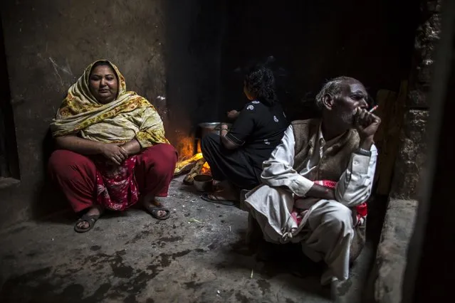 A women cooks,as her family members sit beside her in their house at a Christian slum in Islamabad December 4, 2014. (Photo by Zohra Bensemra/Reuters)