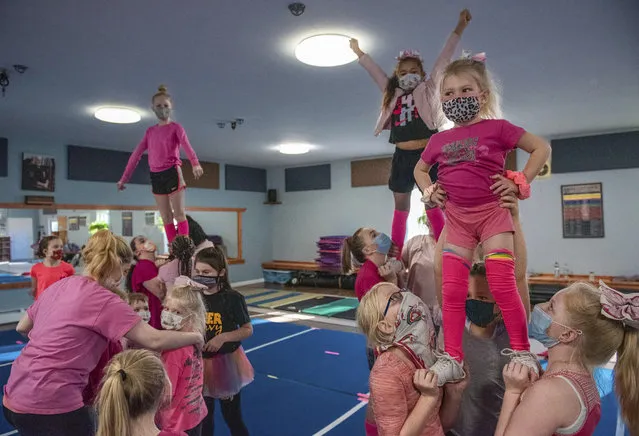 Miyah Provencher, 4, right, settles into her pose at the top of a cheerleading formation at a Cheer Envy practice at Pelletier's Karate Academy in Lewiston, Maine, on Sunday, October 26, 2020. Cheering sessions have recently resumed, with all participants required to wear masks during practices. Cheerleaders were wearing pink in recognition of Breast Cancer Awareness Month.(Photo by Andree Kehn/Sun Journal via AP Photo)