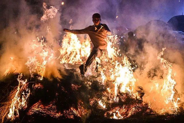 People jump cross the bonfire on February 28, 2023 in Jieyang,Guangdong Province of China.The citizens held a fire jumping activity to pray for the elimination of bad luck. (Photo by John Ricky/Anadolu Agency via Getty Images)