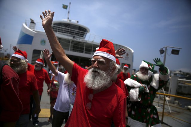 Students of the "Escola de Papai Noel do Brasil" (Brazil's school of Santa Claus) greet people as they arrive from the Guanabara bay after their graduation ceremony onboard a ferry, in Rio de Janeiro, Brazil, November 10, 2015. (Photo by Pilar Olivares/Reuters)