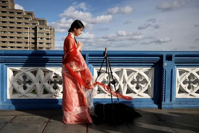 A Chinese student who calls herself Evie makes a video for her followers on Douyin, a Chinese social media network similar to Tiktok, on Tower Bridge in London, Britain on March 25 2023. (Photo by Kevin Coombs/Reuters)