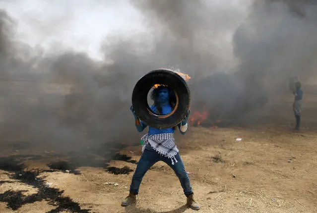 A demonstrator with his face painted like a character from the movie “Avatar” carries a burning tire during a protest where Palestinians demand the right to return to their homeland, at the Israel-Gaza border in the southern Gaza Strip, May 3, 2018. (Photo by Ibraheem Abu Mustafa/Reuters)