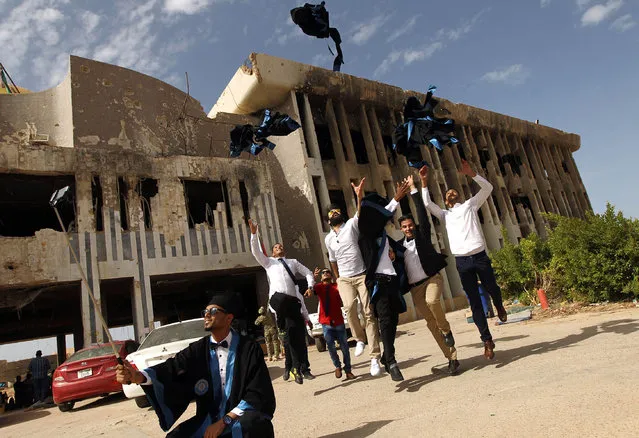 Students from the chemical engineering department of Benghazi University throw their academic dresses in the air as they celebrate on October 24, 2016, during their graduation ceremony in front of a building of the university that was destroyed due to fighting. (Photo by Abdullah Doma/AFP Photo)
