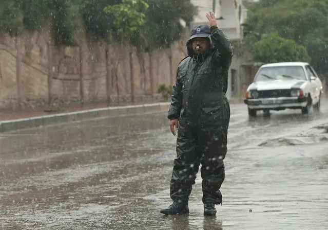 A Palestinian traffic police gestures as he works on a rainy day, in Gaza City November 17, 2015. (Photo by Mohammed Salem/Reuters)