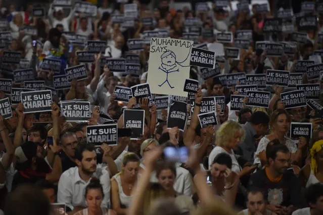 Members of Sydney's French community gather in the heart of the city to hold aloft banners reading “Je Suis Charlie” (I am Charlie) on January 8, 2015, in tribute to the victims killed after gunmen opened fire in the offices of French satirical weekly Charlie Hebdo  in Paris the day before. (Photo by Peter Parks/AFP Photo)
