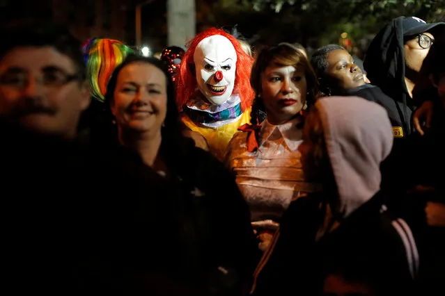 A person dressed in a clown costume stands amongst attendees during the Greenwich Village Halloween Parade in Manhattan, New York, U.S., October 31, 2016. (Photo by Andrew Kelly/Reuters)