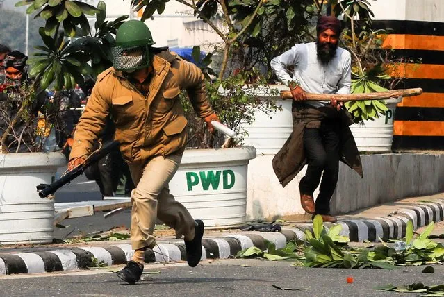 A farmer runs behind a police officer during a protest against farm laws introduced by the government, in New Delhi, India, January 26, 2021. (Photo by Adnan Abidi/Reuters)