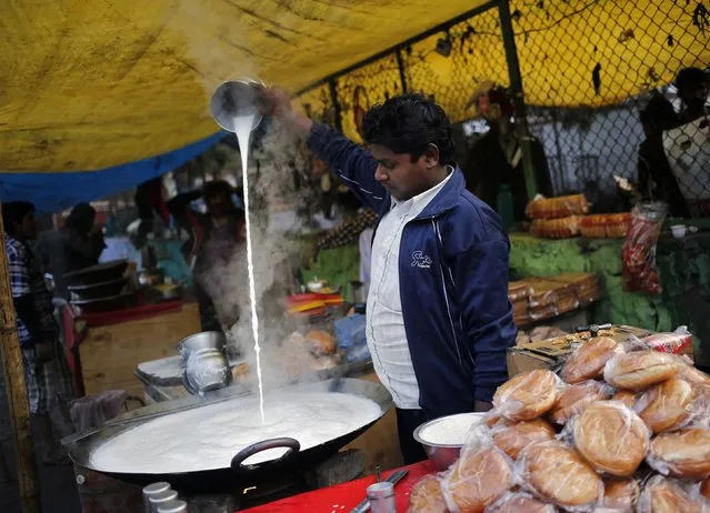 A vendor pours milk to cool it-off before serving it to the customers at a makeshift roadside shop in New Delhi January 15, 2015. (Photo by Anindito Mukherjee/Reuters)