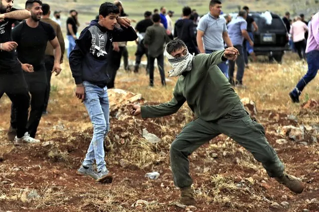 A Lebanese protester throws stones at Israeli troops on the outskirts of the Lebanese village of Kfar Chouba, south Lebanon, Friday, June 9, 2023. Israeli soldiers fired tear gas to disperse scores of protesters who pelted the troops with stones along the border with Lebanon Friday, leaving some Lebanese demonstrators and troops suffering breathing problems. The tension on the edge of the Lebanese border village of Kfar Chouba began earlier this week over the Israeli military digging in the area that Lebanon claims. (Photo by Mohammad Zaatari/AP Photo)