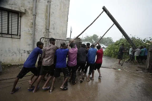 Workers fix a pole to restore electricity following heavy winds and incessant rains after landfall of cyclone Biparjoy at Mandvi in Kutch district of Western Indian state of Gujarat, Friday, June 16, 2023. (Photo by Ajit Solanki/AP Photo)