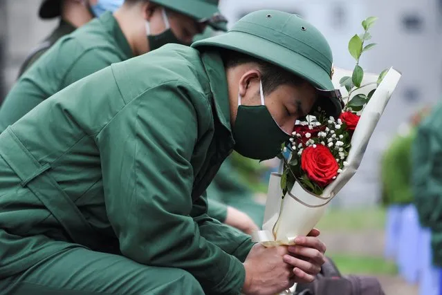 Nguyen Hoang Viet, 22 years old, a new military recruit, wearing a face mask amid the spread of the coronavirus disease (COVID-19), holds a bouquet as he attends a ceremony before leaving for military service in Hanoi, Vietnam, February 27, 2021. (Photo by Thanh Hue/Reuters)
