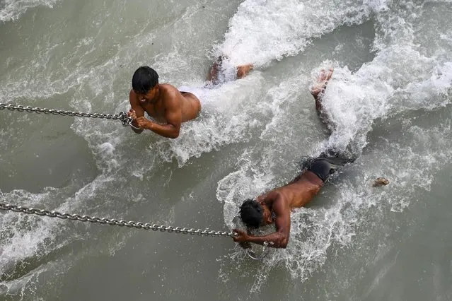 Hindu devotees take a holy dip in the waters of the River Ganges on the eve of Shahi Snan (grand bath) on Maha Shivratri festival during the ongoing religious Kumbh Mela festival in Haridwar on March 10, 2021. (Photo by Prakash Singh/AFP Photo)