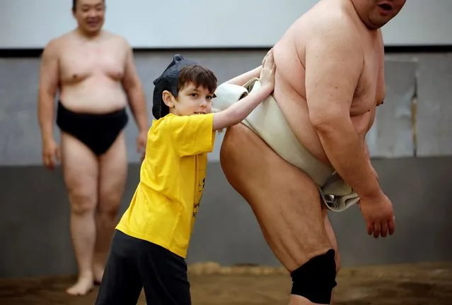 Theo, a 9-year-old child from Australia, tries to spar against former sumo wrestler Towanoyama on the sumo ring before tourists from abroad, at Yokozuna Tonkatsu Dosukoi Tanaka in Tokyo, Japan on June 30, 2023. (Photo by Issei Kato/Reuters)