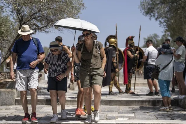 Tourists exit the ancient Acropolis of Athens as the Greek culture ministry shut down the monument most of the day because of heat, Friday, July 14, 2023. Temperatures were starting to creep up in Greece, where a heatwave was forecast to reach up to 44 degrees Celsius in some parts of the country over the weekend. (Photo by Petros Giannakouris/AP Photo)