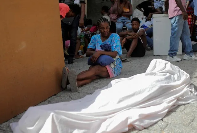 Asefie David sits next to the body of her son Peterson Gerome, who was killed by gang members after they took over the neighbourhood Carrefour Feuilles, in Port-au-Prince, Haiti on August 15, 2023. (Photo by Ralph Tedy Erol/Reuters)