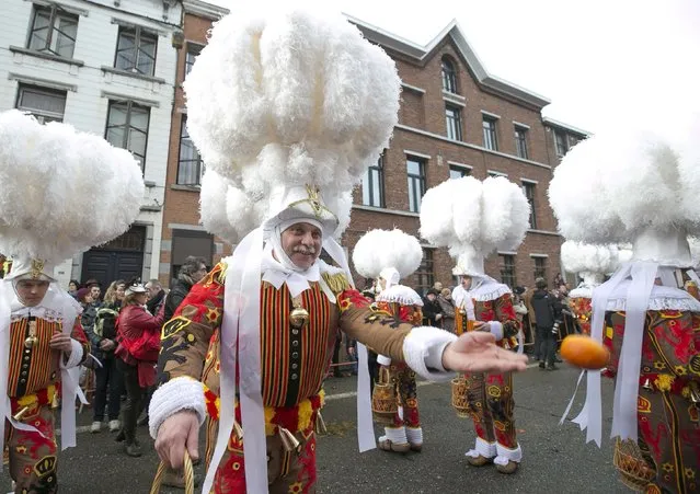 A Gille of Binche throws an orange while taking part in the parade during the carnival event in Binche February 17, 2015. (Photo by Yves Herman/Reuters)